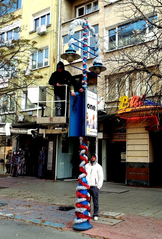 Работници поставят украса по лампите на "Витошка" от снощи.